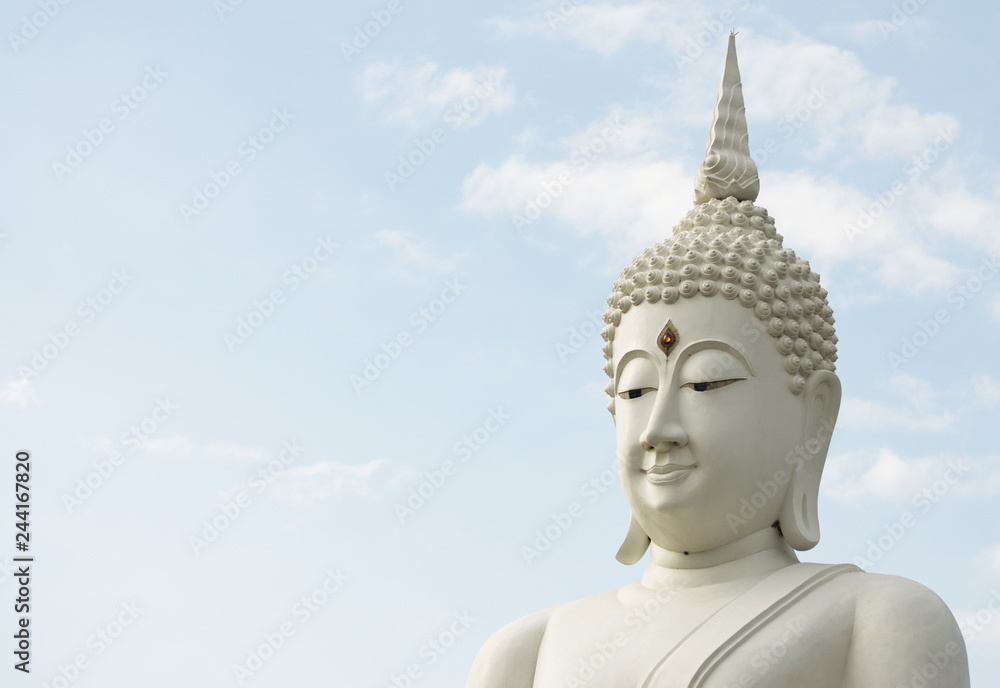 White Buddha statue on sky background.