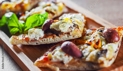 sliced vegetarian pizza with Mozzarella cheese, olives, mushrooms, pepper and fresh basil. Italian pizza on wooden table background