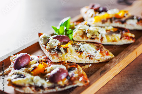 sliced vegetarian pizza with Mozzarella cheese, olives, mushrooms, pepper and fresh basil. Italian pizza on wooden table background