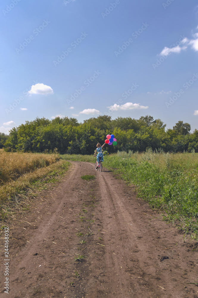 woman in dress on bicycle with colorful balloons woman in dress on bicycle with colorful balloons