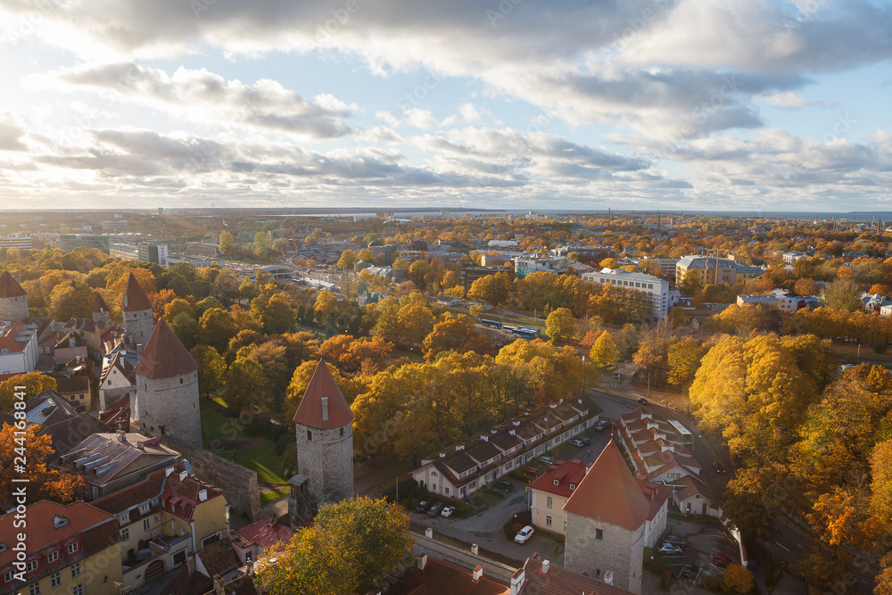TALLINN, ESTONIA - OCTOBER 15, 2017: Aerial view on the foliage around old town towers and wall, Tallinn, Estonia. Bright autumn day.