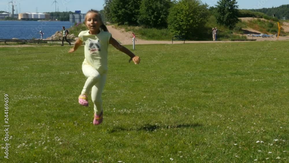 Kid running on the green field. Little girl walking and runs on the green grass. Child walking and playing Kid running on the green field. Little girl walking and runs on the green grass. Child walking and playing