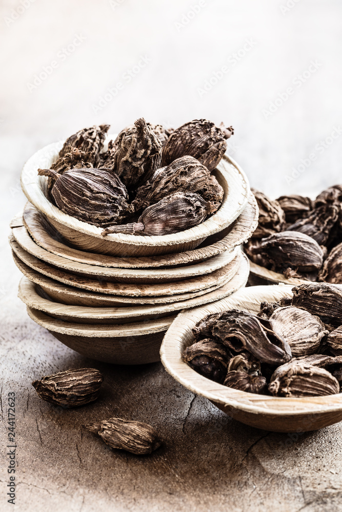 Black cardamom in bowls on wooden rustic background indian spice. Black cardamom in bowls on wooden rustic background indian spice.