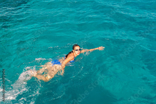 Woman swimmer swimming crawl in blue sea. Woman swiming in the sea. Happy young woman in a blue swimsuit in the sea on vacation. copy space