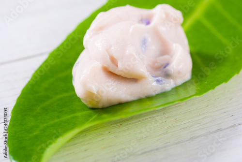cosmetic cream on herbal leaf, white wood background