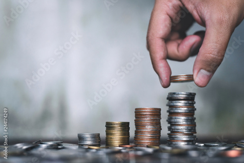 Save money concept with hand holding coin and stack growing business on abstract background