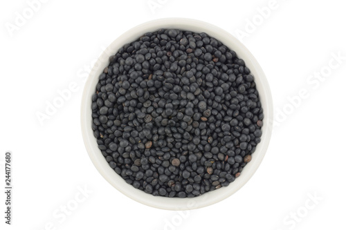 Lenteja caviar negra en un bol de cerámica blanca sobre fondo blanco, top view