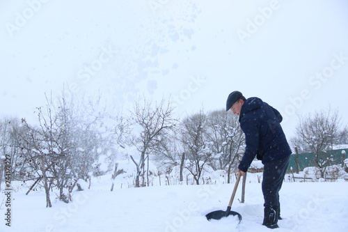 man cleans snow in the backyard