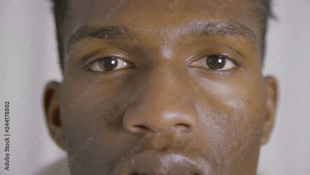 Extreme close-up of young African American man. Face of young guy looking at camera. Young man concept Extreme close-up of young African American man. Face of young guy looking at camera. Young man concept