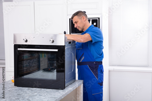 Male Technician Repairing Oven