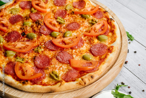 Delicious pizza Neapolitana with tomato sauce, mozzarella and ham on the white wooden background