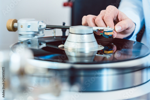 Woman putting needle on vinyl record on turntable photo