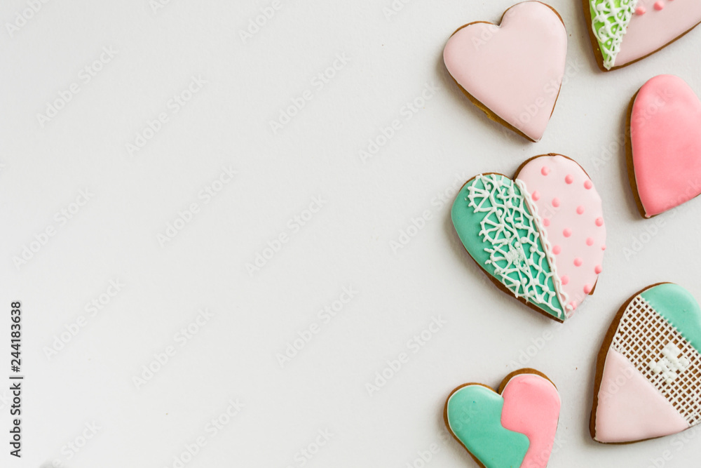 Obraz premium Painted pink and colored, ginger and honey cakes and cookies. In the shape of a heart. On a light wooden background. Frame. Place for text. The concept of love, mother's day, cooking, St. Valentine.