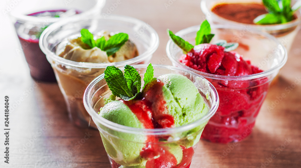 various ice cream desserts a plastic cups with mint leaf on wooden table various ice cream desserts a plastic cups with mint leaf on wooden table