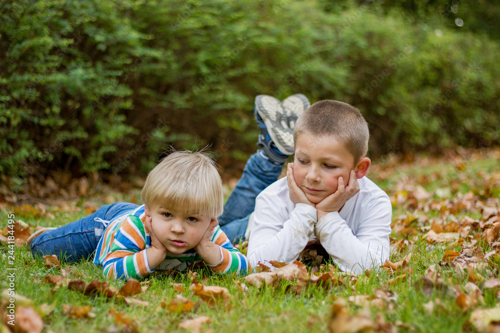 Cute little brother childrens lying on green grass in park Cute little brother childrens lying on green grass in park