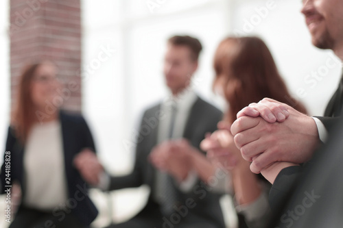 Business group in a circle holding hands indoors