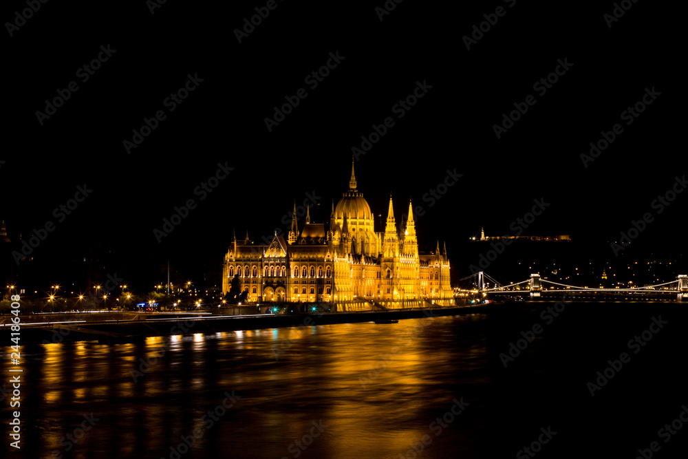 Budapest Parliament in Hungary at night on the Danube river with bridge view.