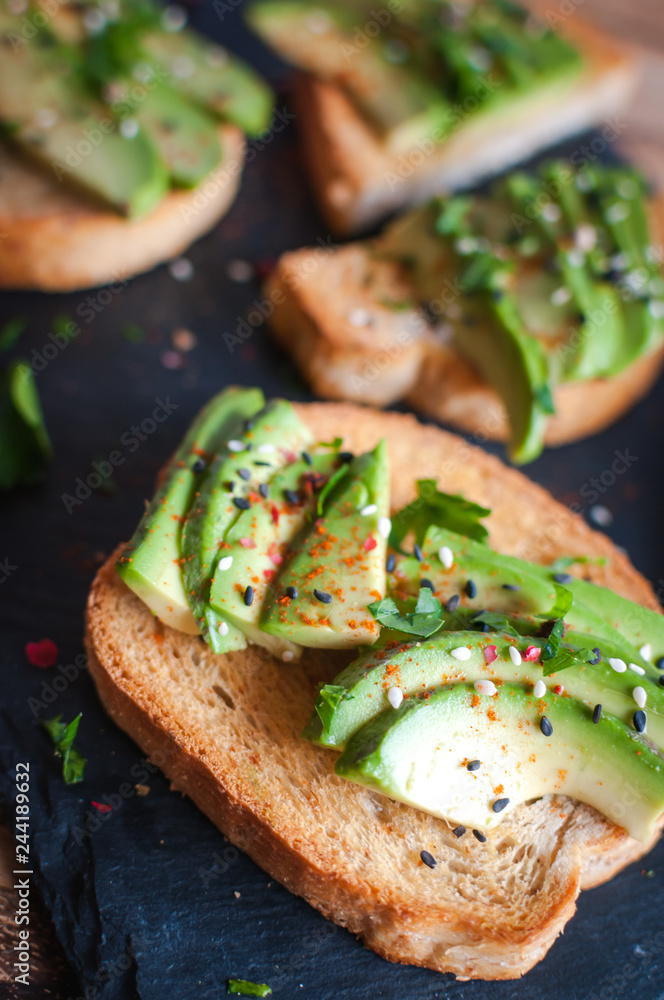 Close-up of fresh avocado toast with spices on dark background Close-up of fresh avocado toast with spices on dark background