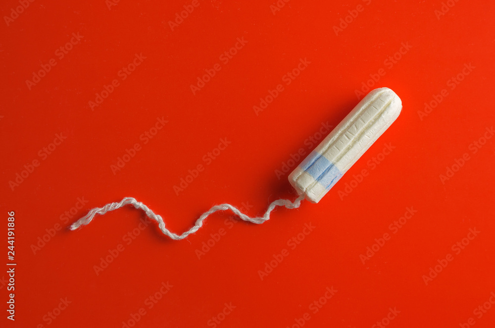 Vaginal cotton tampon with thread on red background. Menstruation concept. Vaginal cotton tampon with thread on red background. Menstruation concept.
