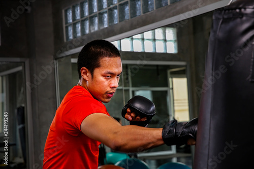 Athletes are punching in the gym. Male action of a boxing fighter training on a punching bag in the gym. Man boxer training is exercising with a punching bag at the sport club. © Thirawatana
