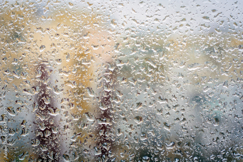 Raindrops on glass, window background view of buildings out of focus.