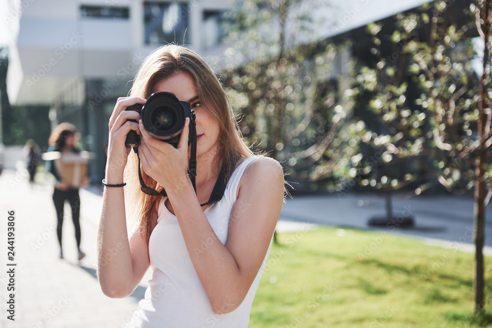 Girl photographer blogger holds in hand a professional camera on the open air in the city Girl photographer blogger holds in hand a professional camera on the open air in the city