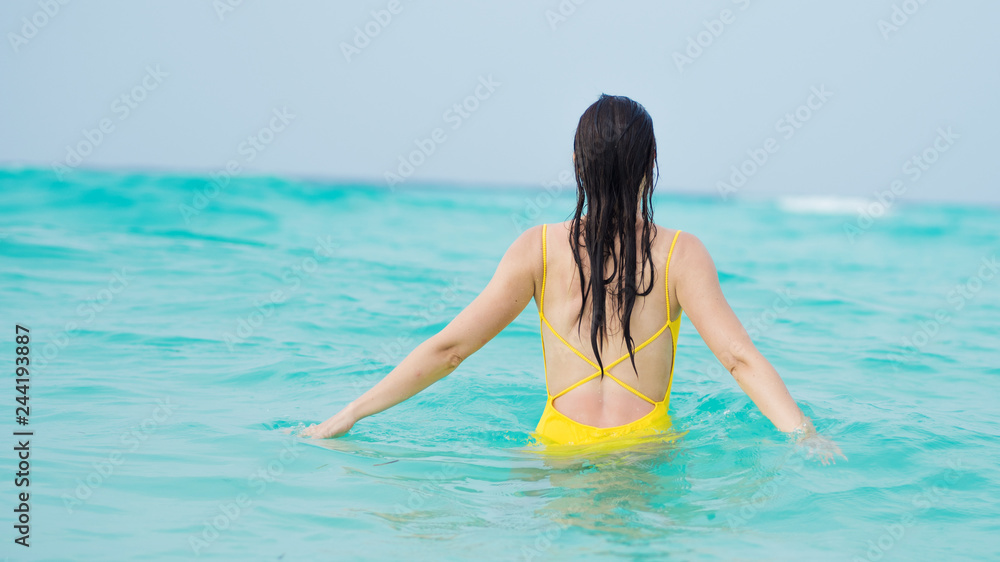 Young brunette woman in yellow one piece swimsuit.