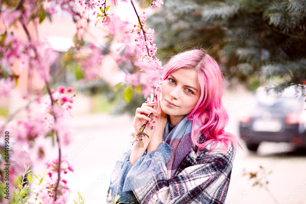 young beautiful girl with pink hair standing near a tree with flowers, pink flowers, spring, sun, happiness young beautiful girl with pink hair standing near a tree with flowers, pink flowers, spring, sun, happiness
