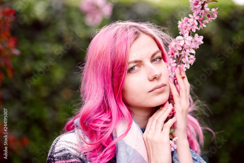 young beautiful girl with pink hair standing near a tree with flowers, pink flowers, spring, sun, happiness