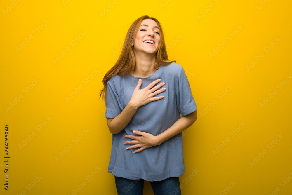 Young redhead girl over yellow wall background smiling a lot while putting hands on chest Young redhead girl over yellow wall background smiling a lot while putting hands on chest