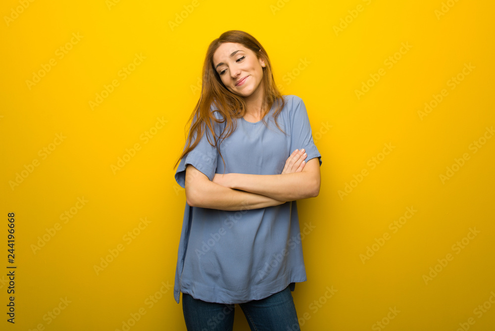 Young redhead girl over yellow wall background making doubts gesture while lifting the shoulders Young redhead girl over yellow wall background making doubts gesture while lifting the shoulders