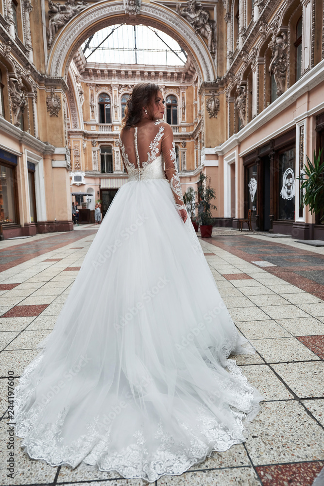 Beautiful, elegant bride with a perfect wedding dress, poses around beautiful architecture.