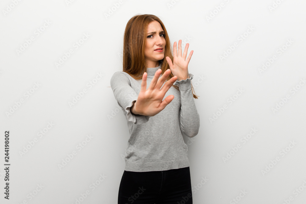 Redhead girl over white wall is a little bit nervous and scared stretching hands to the front Redhead girl over white wall is a little bit nervous and scared stretching hands to the front