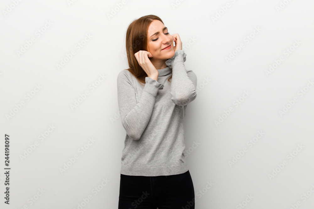 Redhead girl over white wall covering ears with hands. Frustrated expression Redhead girl over white wall covering ears with hands. Frustrated expression