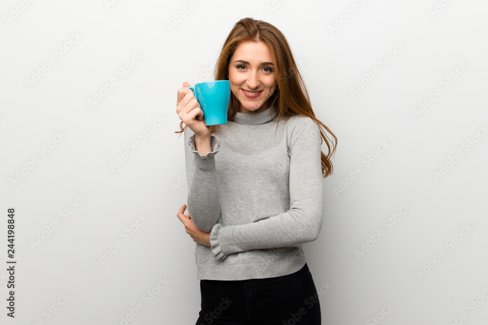 Redhead girl over white wall holding a hot cup of coffee Redhead girl over white wall holding a hot cup of coffee