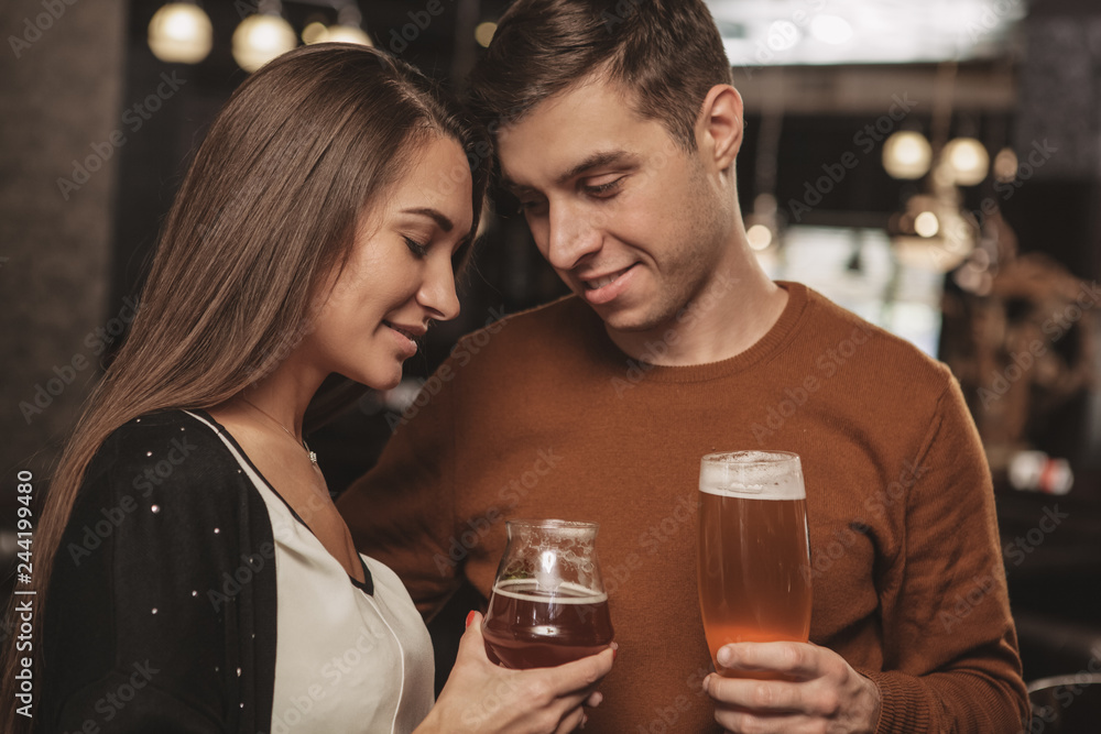 Beautiful affectionate couple cuddling, while having drinks together at the bar. Handsome man embracinghis beautiful girlfriend, celebrating anniversary at the restaurant Love, romance, valentines day Beautiful affectionate couple cuddling, while having drinks together at the bar. Handsome man embracinghis beautiful girlfriend, celebrating anniversary at the restaurant Love, romance, valentines day
