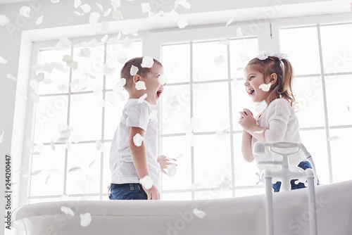 Child playing with rose petals in home bathroom. Little girl and boy fawing fun and joy together. The concept of childhood and the realization of dreams  fantasy  imagination