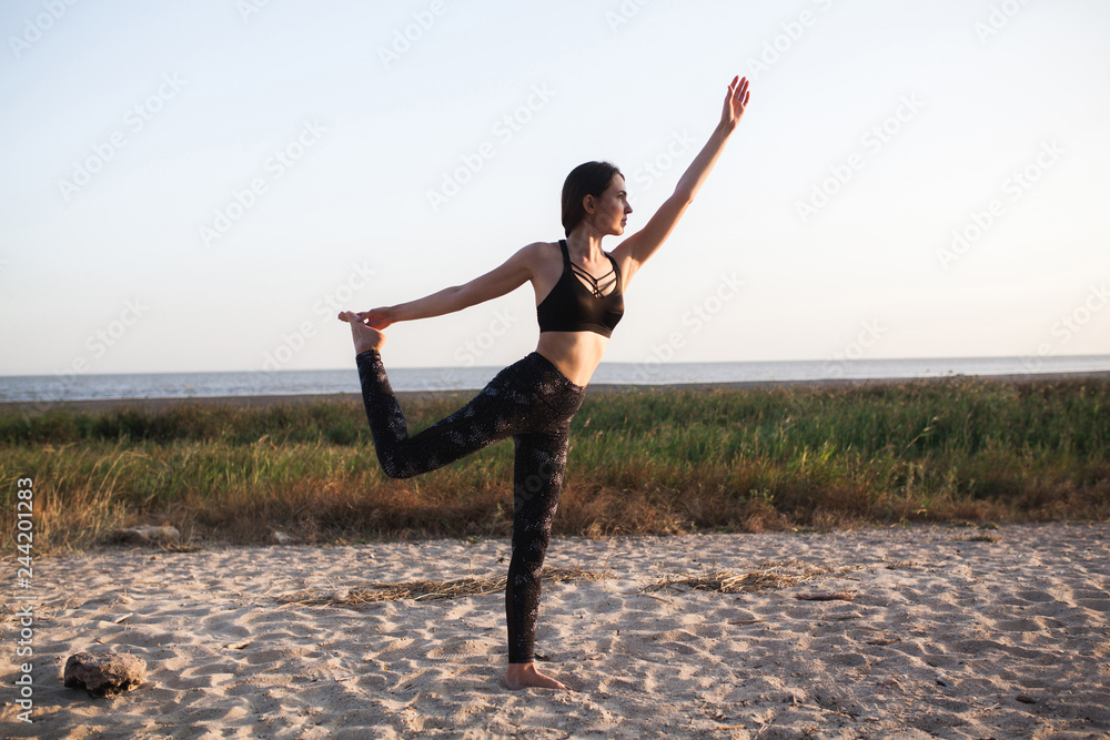 Slim brunette young Woman Practicing Yoga At sand beach. Copy space. Healthy style sport. virabhadrasana