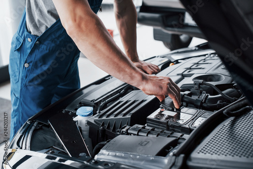 Mechanic hands checking up of serviceability of the car in open hood, close up.