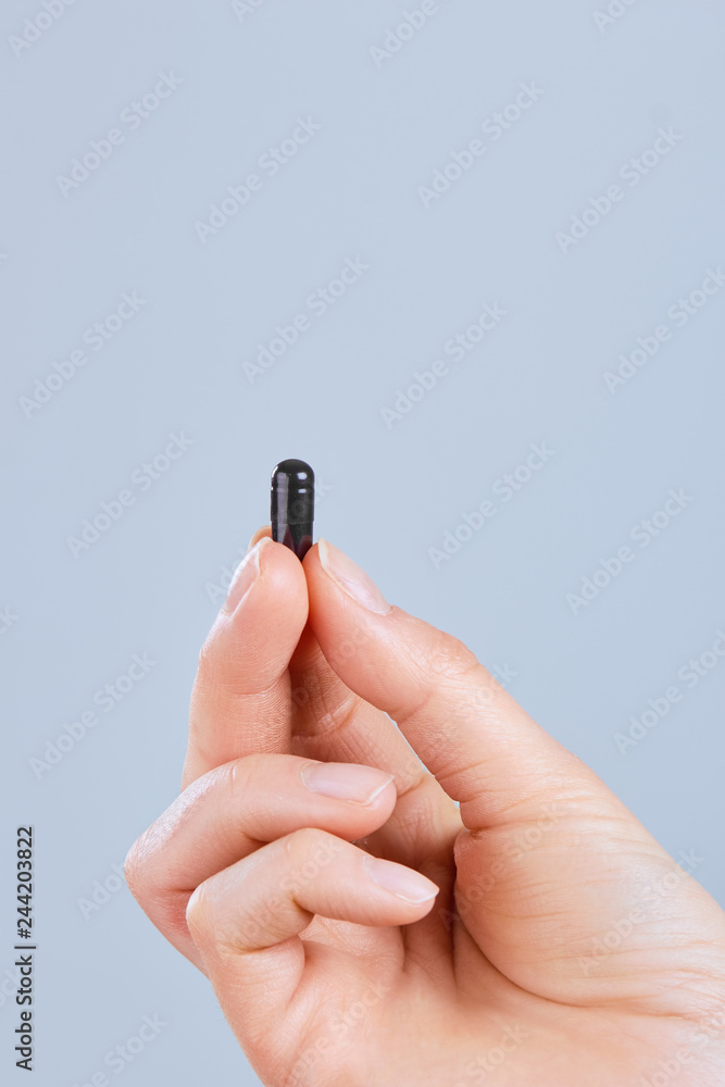 Hand holding black activated carbon capsule for food poisoning treatment - Image.Vitamins And Dietary Supplements. Hand holding black activated carbon capsule for food poisoning treatment - Image.Vitamins And Dietary Supplements.
