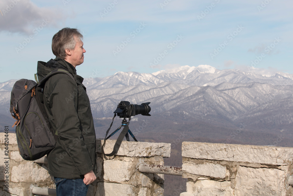 Photographer travels and takes pictures. Location in the mountains. Photographer shooting nature with professional camera