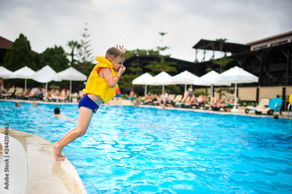 a 6-year blond boy in a life vest jumping in the swimming pool of a hotel in Turkey