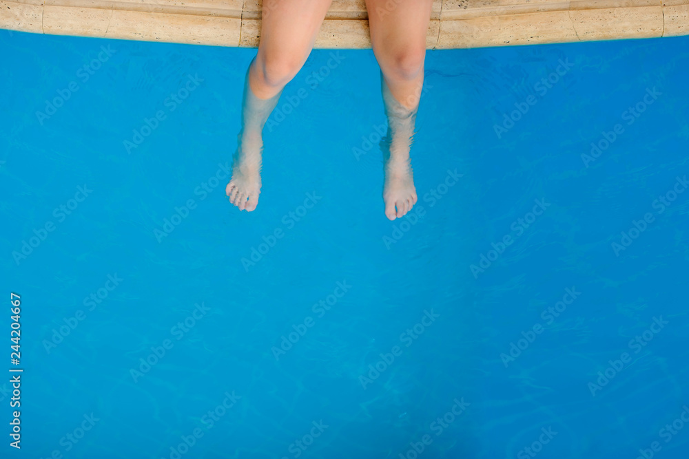 child's legs in the water of a swimming pool