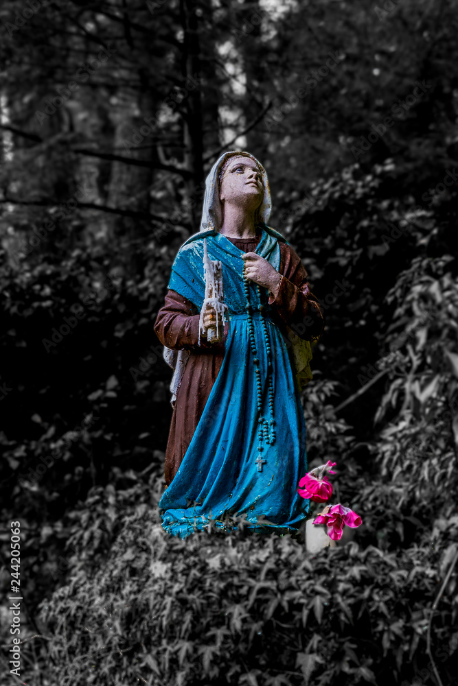 beautiful image of a statue of Bernadette praying to Our Lady of Lourdes with a dark background in Vielsalm in the Belgian Ardennes