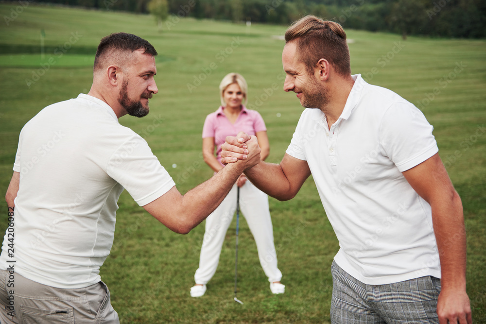 Fototapeta premium Three players play on the golf course. The team congratulates and shakes hands with each other