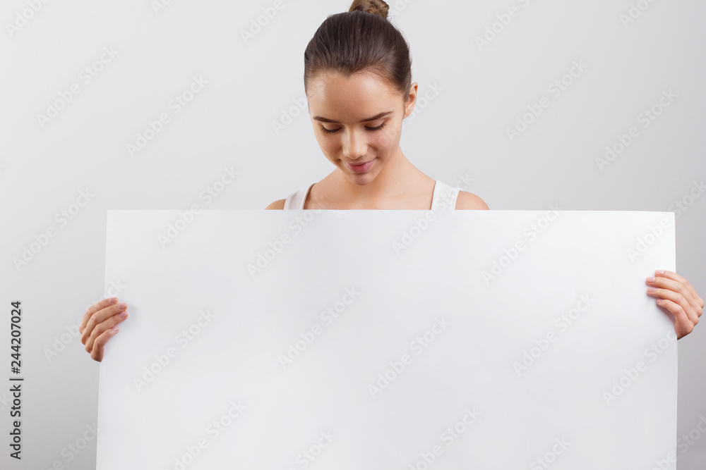 Portrait of a beautiful brunette woman holding a white blank banner. Portrait of a beautiful brunette woman holding a white blank banner.