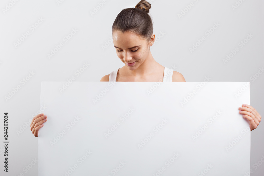 Portrait of a beautiful brunette woman holding a white blank banner. Portrait of a beautiful brunette woman holding a white blank banner.