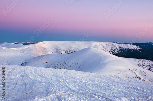 Beautiful alpine panoramic views of the snow-capped mountains. Magic pink Sunrise in the mountains in a winter frosty day. Location Carpathian national park, Ukraine, Europe. Alpine ski resort.