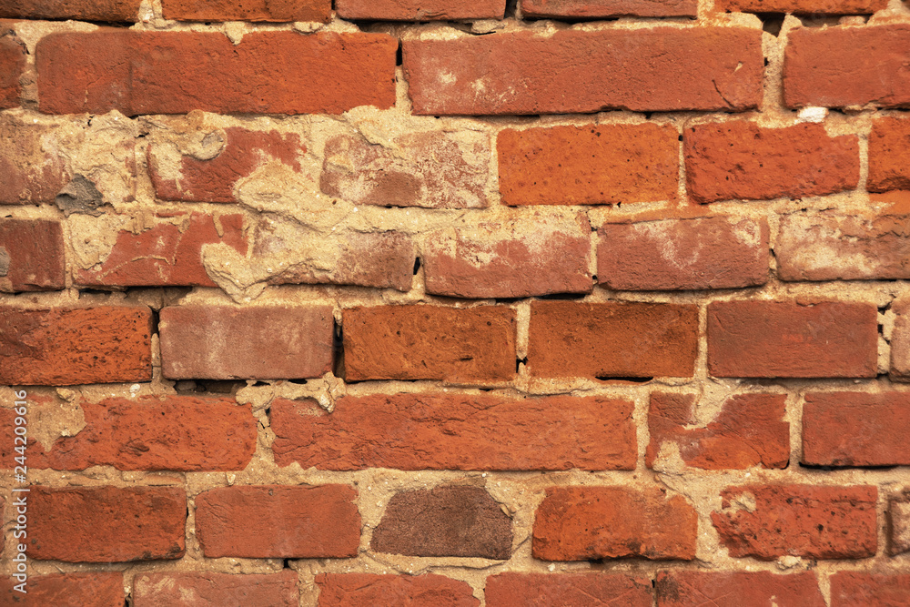 An old red brick wall, with peeling plaster and a covered stone. An old red brick wall, with peeling plaster and a covered stone.