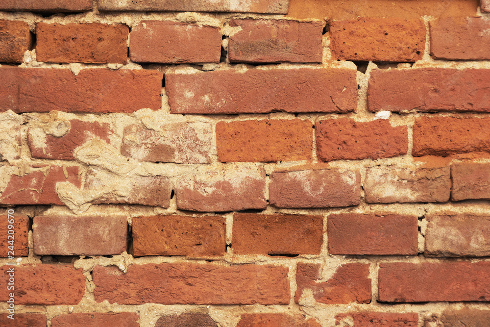 An old red brick wall, with peeling plaster and a covered stone. An old red brick wall, with peeling plaster and a covered stone.